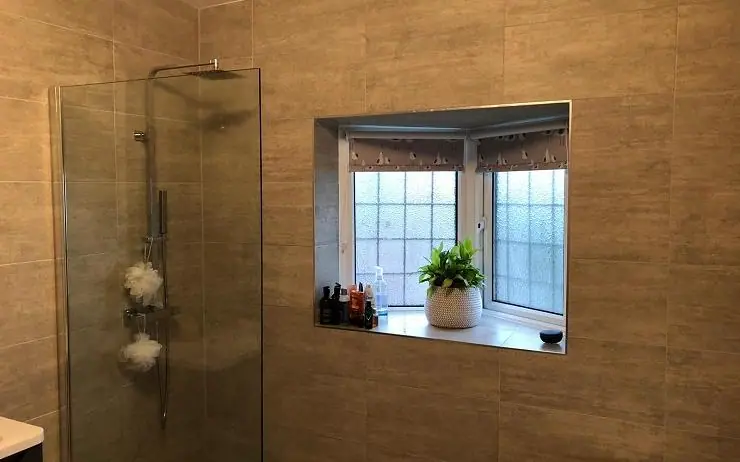 Tiled bathroom with a glass shower enclosure and chrome fittings
