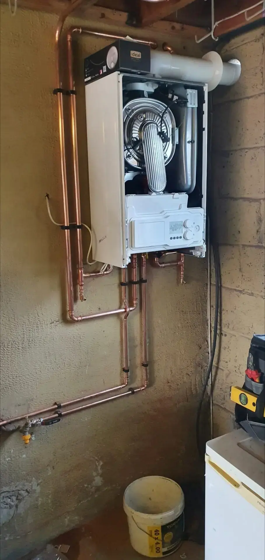 Ideal boiler with its front cover off, showing the internal components and copper pipework